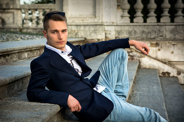 istock Attractive blond young man sitting on stone stair steps outside 534679881
