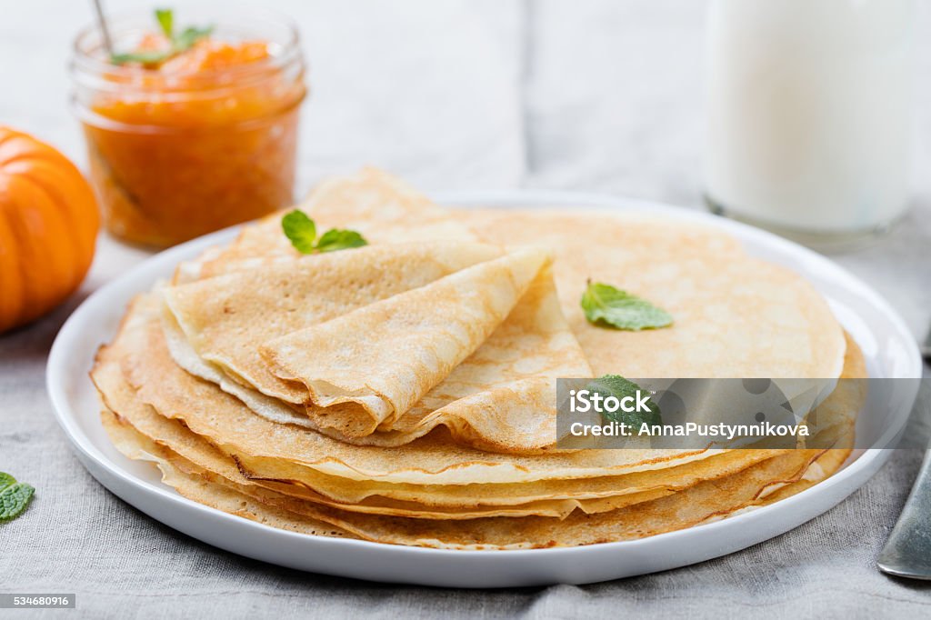 Thin crepes or pancakes with butter, honey and sour cream Thin crepes or pancakes with butter, honey and sour cream on a rustic textile background. Baked Stock Photo