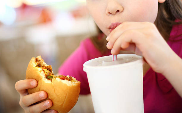 istock Little girl eating burger and drinking soda. 534700203