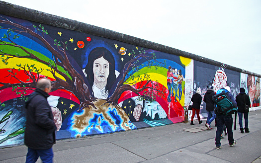 Berlin, Germany - November 10, 2013: People walking near East Side Gallery in Berlin, Germany. It's a 1.3 km long part of original Berlin Wall which collapsed in 1989, and now is the largest world amateur art gallery of graffiti