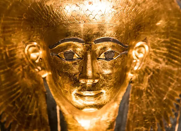 Gold-coloured replica model of an ancient Egyptian pharoah sarcophagus. Macro image studio shot. Horizontal colour image with copy space.