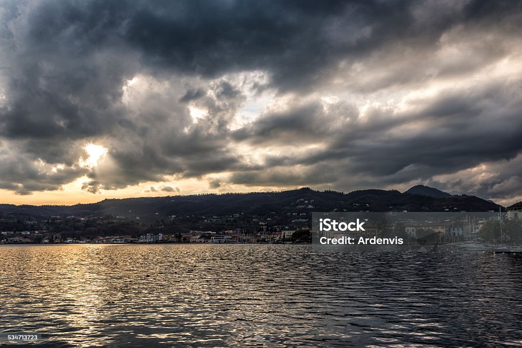 Lago di Garda sotto un cielo nuvoloso e raggi solari - Foto stock royalty-free di 2015