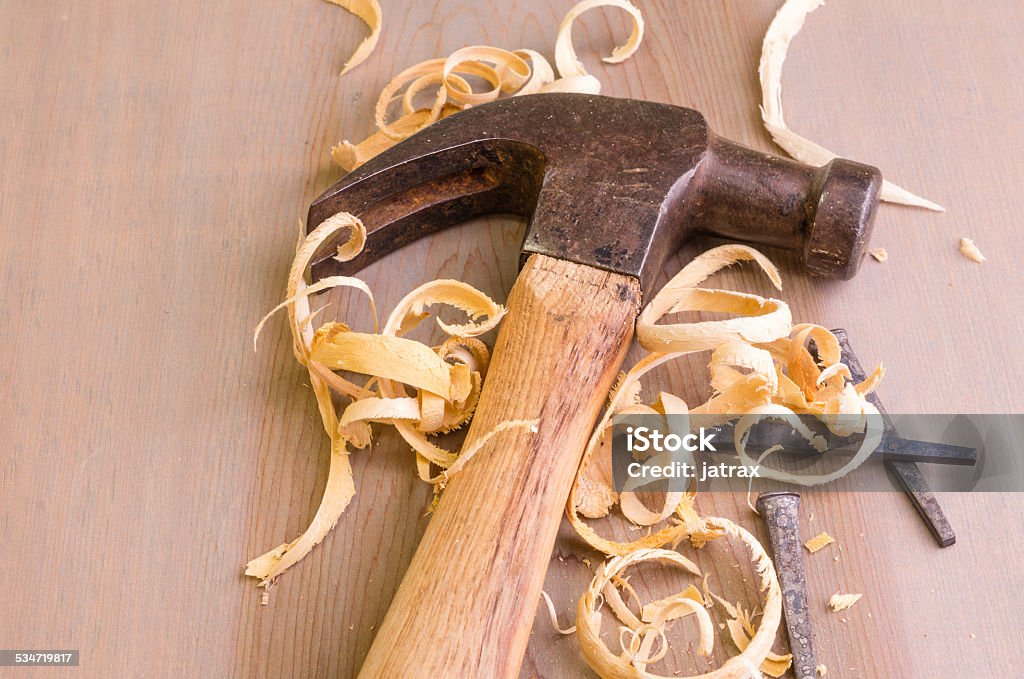 Hammer and nails on a wood board A hammer and nails on a wood board with sawdust shavings 2015 Stock Photo