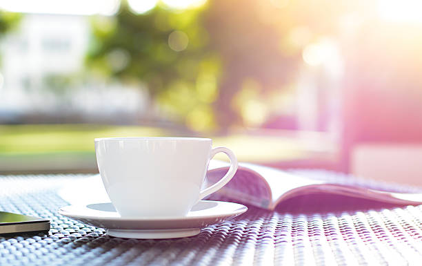 istock Coffee cup with book on blurred green nature background 534720913
