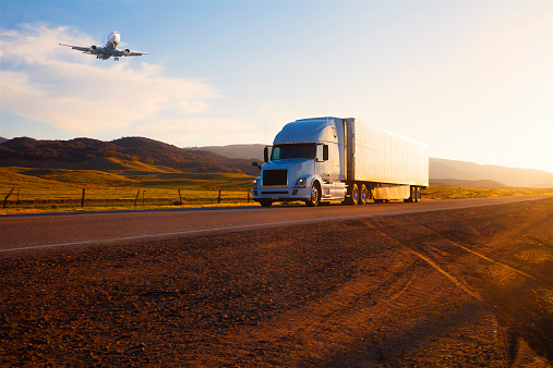 Transportation: Airplane and Truck on highway at sunset, California, USA.