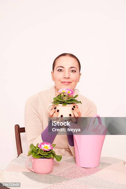 Woman Sitting At Table With Primrose Flowers Stock Photo - Download Image Now - 2015, Adult, Adults Only