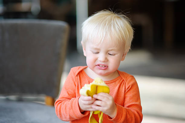 Toddler boy eating banana