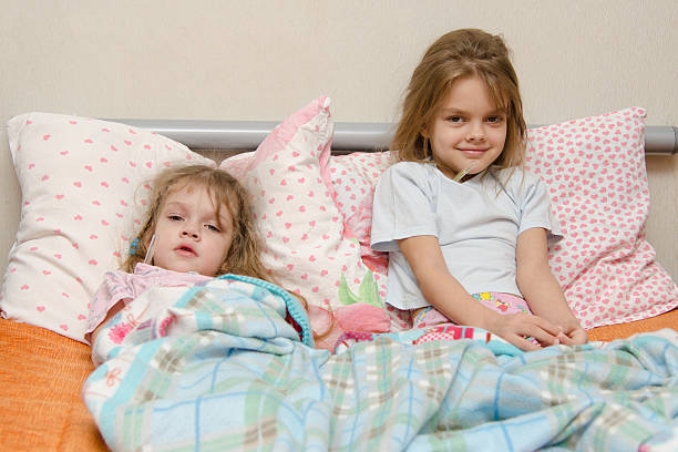 istock Two girls sick in bed with a thermometer 534743253