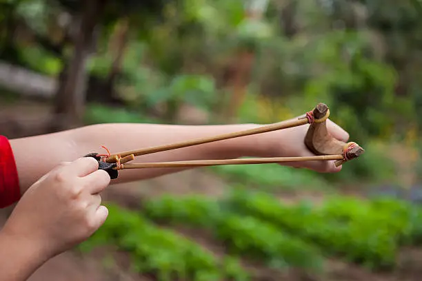 Hand boy pulling sling shot.