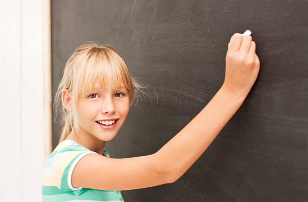 istock Pretty school girl writing on the black board 534759285