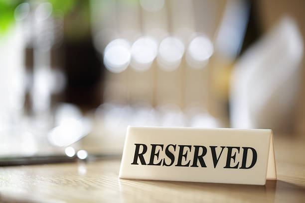 Reserved sign on restaurant table Restaurant reserved table sign with places setting and wine glasses reserved stock pictures, royalty-free photos & images