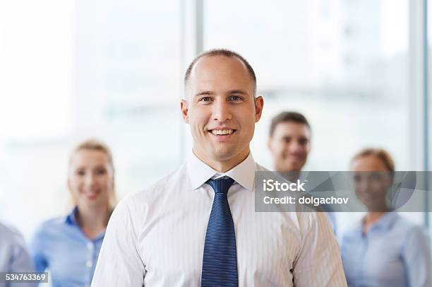 Smiling Businessman With Colleagues In Office Stock Photo - Download Image Now - 2015, Adult, Business