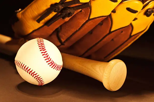 Photo of Baseball glove, bat and ball over a dark background