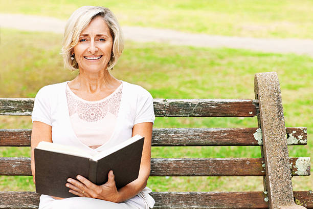 istock Senior Woman Sitting On Park Bench With Book 534781829
