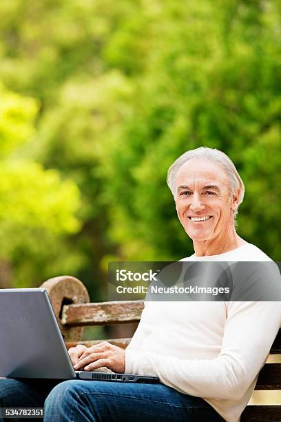 Senior Man Sitting On Park Bench With Laptop Stock Photo - Download Image Now - 2015, 50-59 Years, Active Seniors