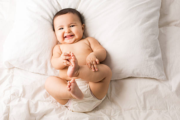 Cute baby girl on bed Close-up of a happy cute baby girl lying on the bed lying on back stock pictures, royalty-free photos & images