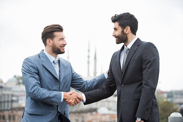 felice affari stringe la mano contro il cielo chiaro di istanbul - middle eastern ethnicity business greeting handshake foto e immagini stock