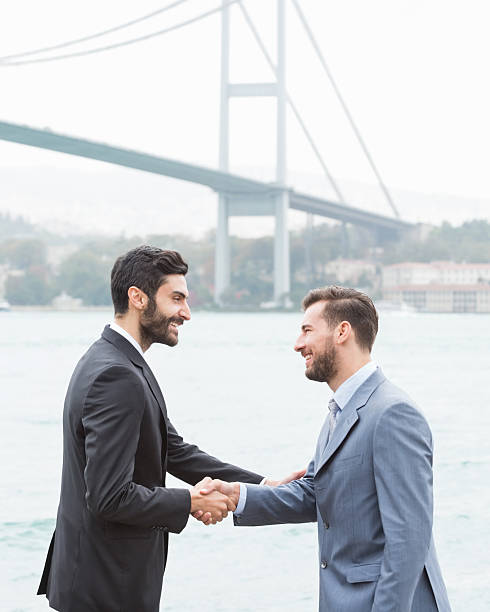 felice affari stringe la mano contro il ponte sul bosforo - middle eastern ethnicity business greeting handshake foto e immagini stock