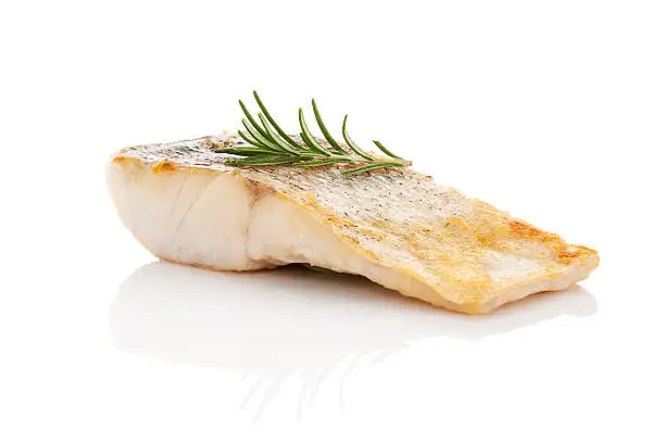 Luxurious seafood dinner. Perch fish fillet isolated on white background with fresh green herbs. Healthy eating.