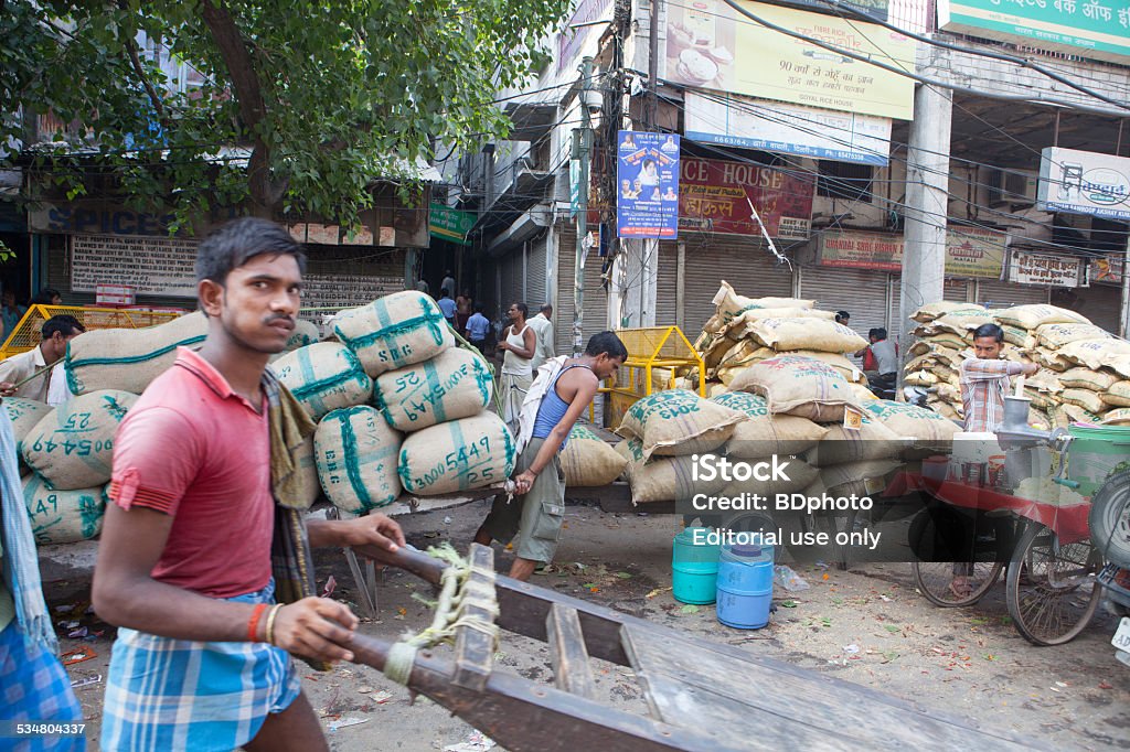 New Delhi daily life New Delhi, India - September 14, 2013.  An Indian porter pushes his cart through the spice market area in the old part of the city.  Adult Stock Photo