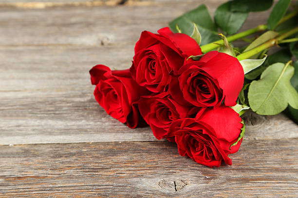 istock Five fresh red roses on grey wooden background 534807895