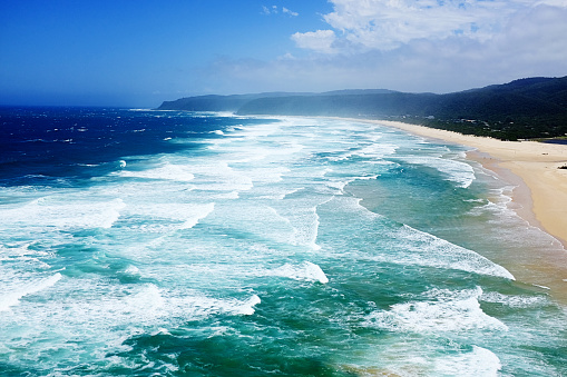 Looking down at the Indian Ocean's waves in multiple shades of blue. This is at Nature's Valley, an unspoilt vacation spot in the eastern part of the Western Cape, South Africa, that is part of a Nature Reserve.