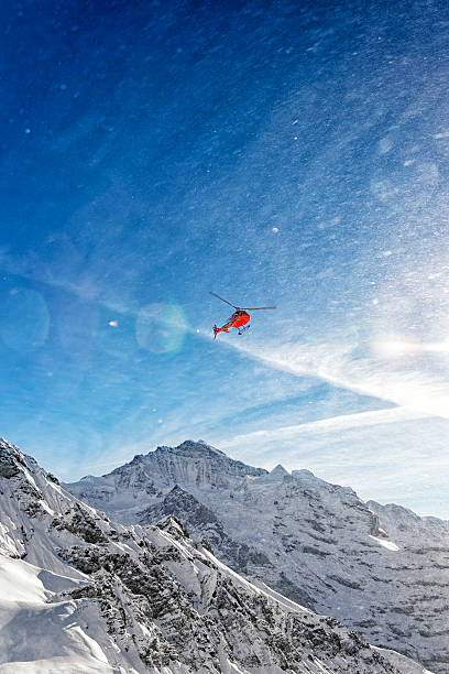 istock Red helicopter in flight in winter alps with snow powder 534824339