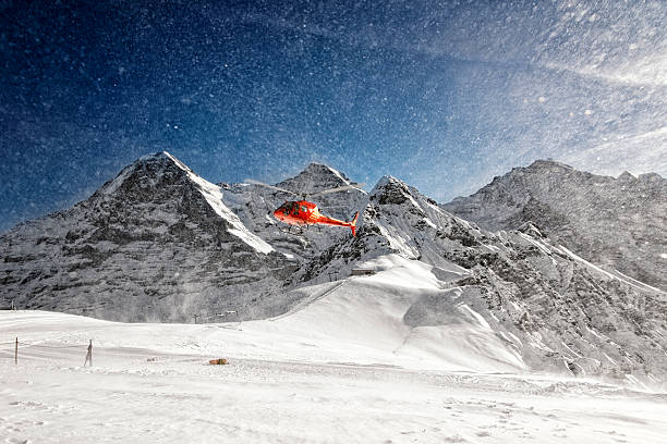 istock Red helicopter taking-off with snow powder clouds from alpine re 534824395