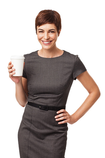 Portrait of happy young businesswoman with hand on hip holding disposable coffee cup against white background. Vertical shot.