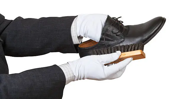 Photo of Shoeshiner in white gloves brushing black shoe