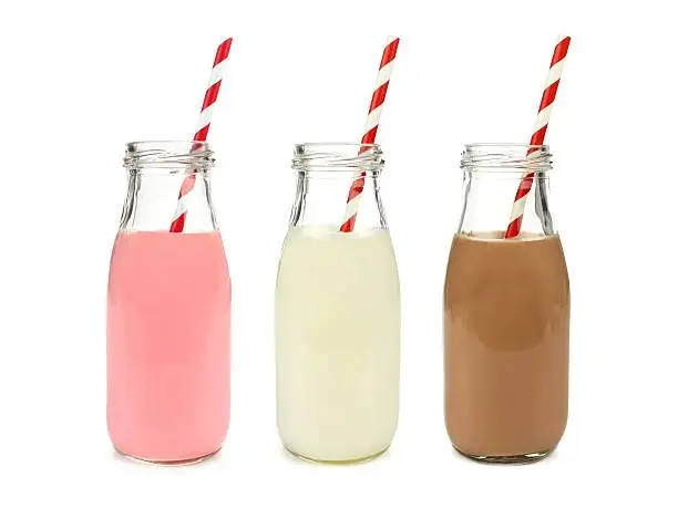 Photo of Strawberry regular and chocolate milk in bottles, isolated