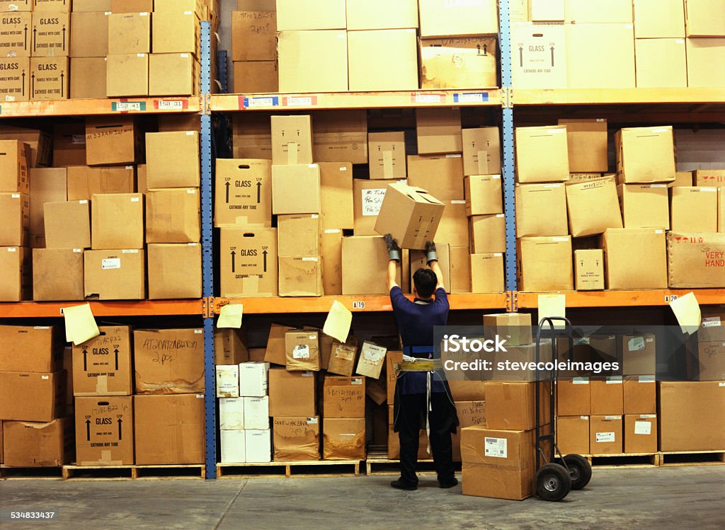 Warehouse Worker placing a box on warehouse shelf. 2015 Stock Photo