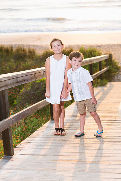 niños de pie en el paseo a lo largo de la playa - beach family boardwalk footpath fotografías e imágenes de stock