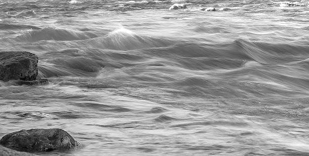 Flowing river with rocks, rapids, whitecaps in Monochrome A river flowing with rapids captured in Monochrome. This river appears to be flowing because of a very long exposure. The water is blurred and there are whitecaps. There are also, still pools of water and rocks in clear focus in the foreground and background. This is an excellent action shot or background. truckee river photos stock pictures, royalty-free photos & images