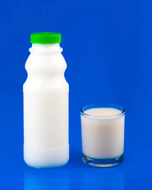Glass of milk and milk-bottle over blue background
