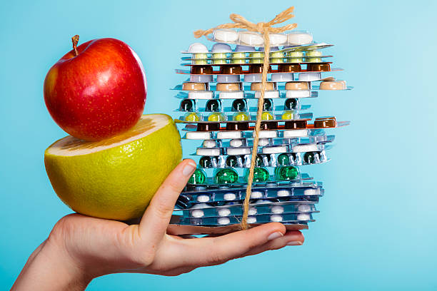 istock Human hand holding stack of pills and fruits on blue. 534863811