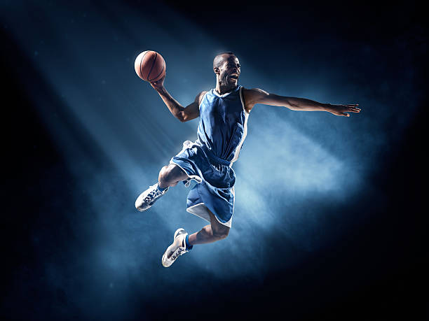 Basketball player in jump shot Close up image of professional basketball player about to do slam dunk during basketball game in floodlight bouncing photos stock pictures, royalty-free photos & images