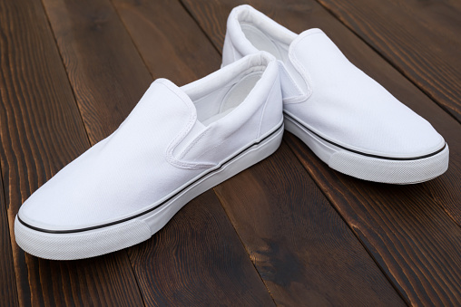 pair of white sneakers on wood