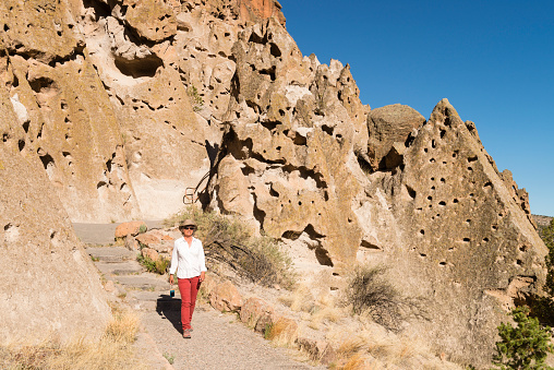 Woman visiting Bandelier National Monument near Santa Fe, New Mexico. Tourist exploring cliff dwellings and nature.