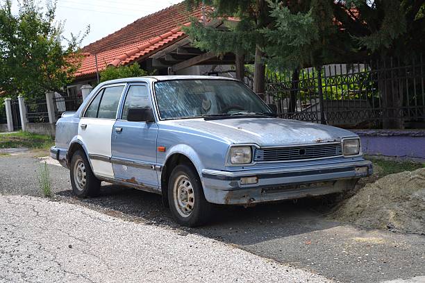 Honda Civic II dying on the street Athens, Greece - August 10th, 2013: Old Honda Civic II sedan dying on the street. The second generation of Civic (1979-1983) was the most popular Honda car in 80s in the world. beat up car stock pictures, royalty-free photos & images