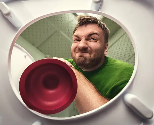 Man cleaning the toilet with cup plunger