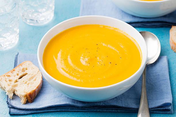 istock Pumpkin and carrot soup with cream on blue stone background. 534880020