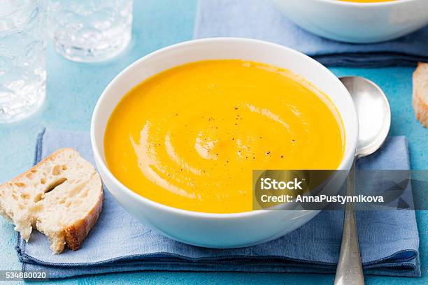 Pumpkin And Carrot Soup With Cream On Blue Stone Background Stock Photo - Download Image Now