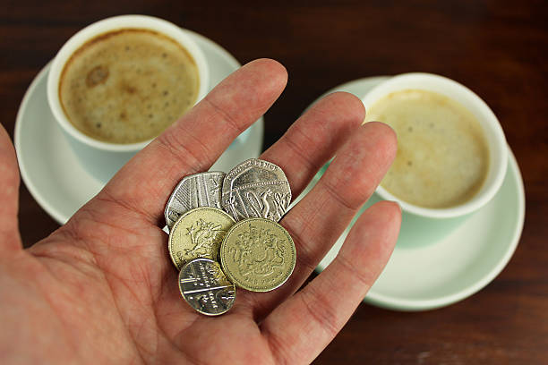 English Currency in hand with two coffee  in background. stock photo