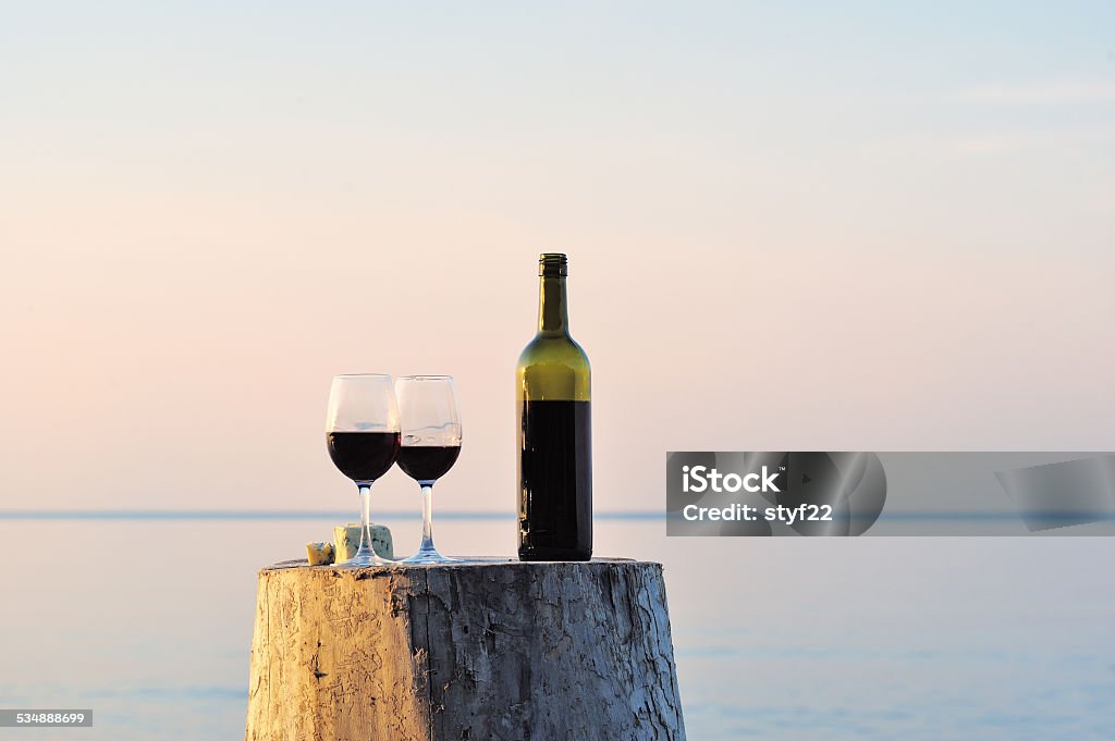 Red wine bottle and wine glasses Red wine bottle and wine glasses on the wooden stump Beach Stock Photo