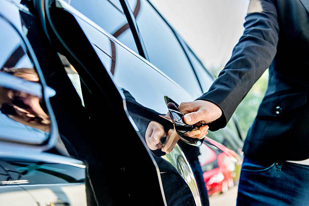 Chauffeur open car door Female chauffeur opening a luxury car door. vehicle door stock pictures, royalty-free photos & images