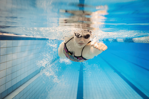 Underwater shot of a young female athlete swimming through an olympic swimming pool.