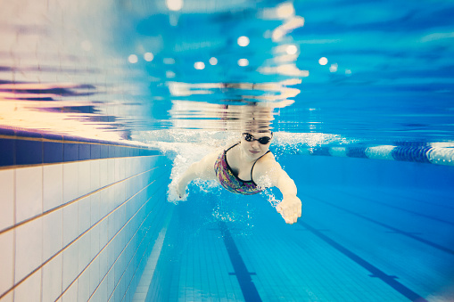 Underwater shot of a young female athlete doing front crawl in an olympic swimming pool.