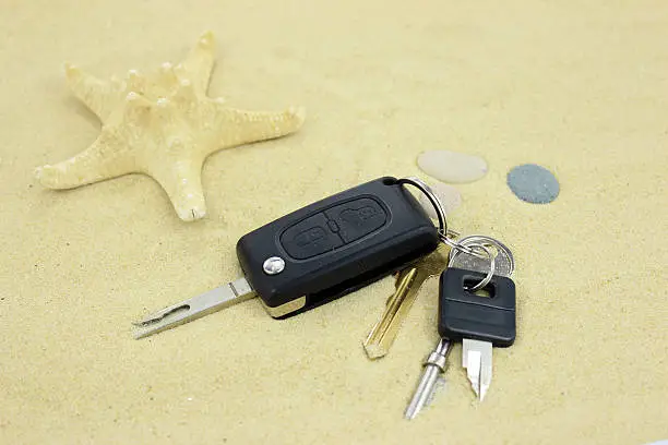 Keys on the sand with starfish. Focus on keys.