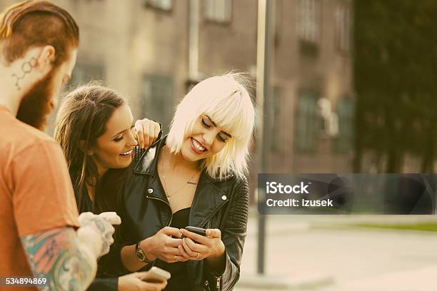 Two Young Woman Using Smart Phones Outdoor Stock Photo - Download Image Now - Blond Hair, Tattoo, 2015